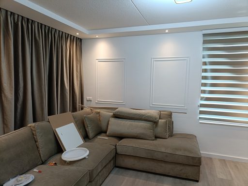 Een lichte woonkamer met een grote hoekbank en verduisterende gordijnen.
