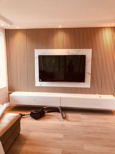 Moderne woonkamer met een wand-tv en een strakke, lichte meubels.