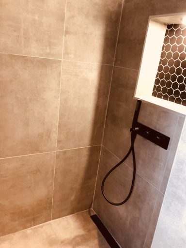 Moderne douche met tegelwanden en een zwarte handdouche.