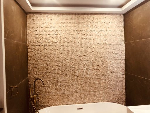 Moderne badkamer met een bad en een stenen wandafwerking.