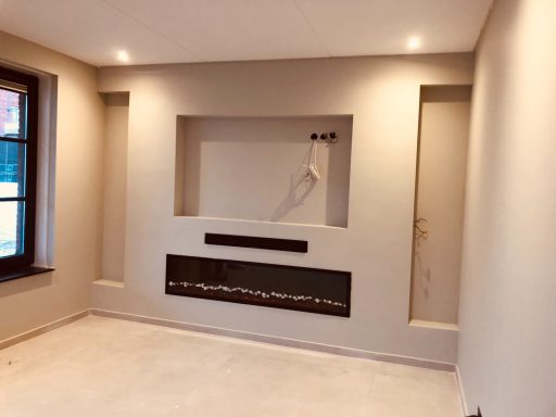 Lege woonkamer met gestucte muren, moderne haard en nis voor wanddecoratie.
