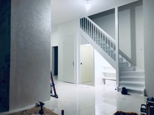 Moderne, lege ruimte met witte muren en een trap naar de bovenverdieping.