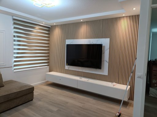 Moderne woonkamer met een wandmontage TV, lichte kleurenschema en subtiele verlichting.