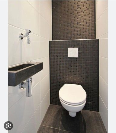 Modern toilet ruimte met zwart tegelwerk en een wandfontein.